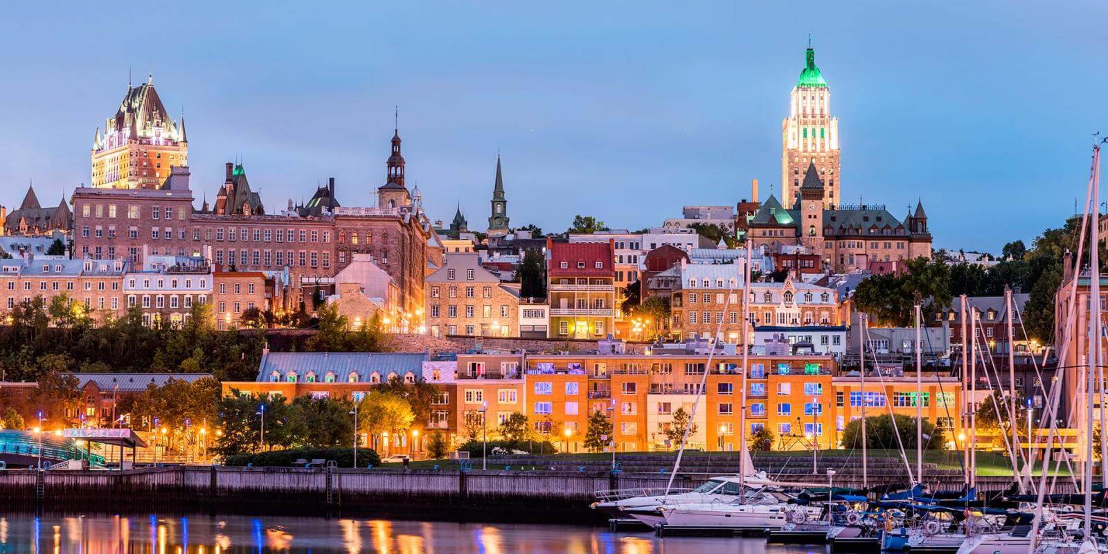 Old Québec at dusk, with the Château Frontenac rising above the lit-up lower town and the marina